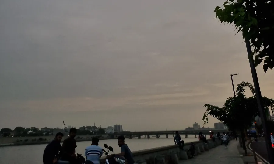 Sabarmati Riverfront at dusk, Ahmedabad — people sitting by the river with the bridge in the background