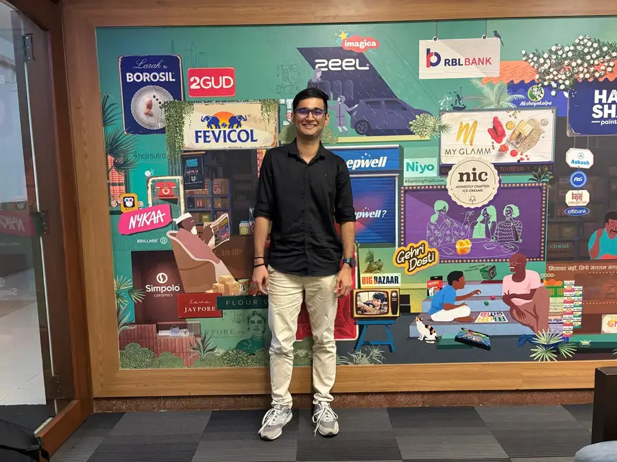 Darsh standing in front of a colourful brand illustration wall