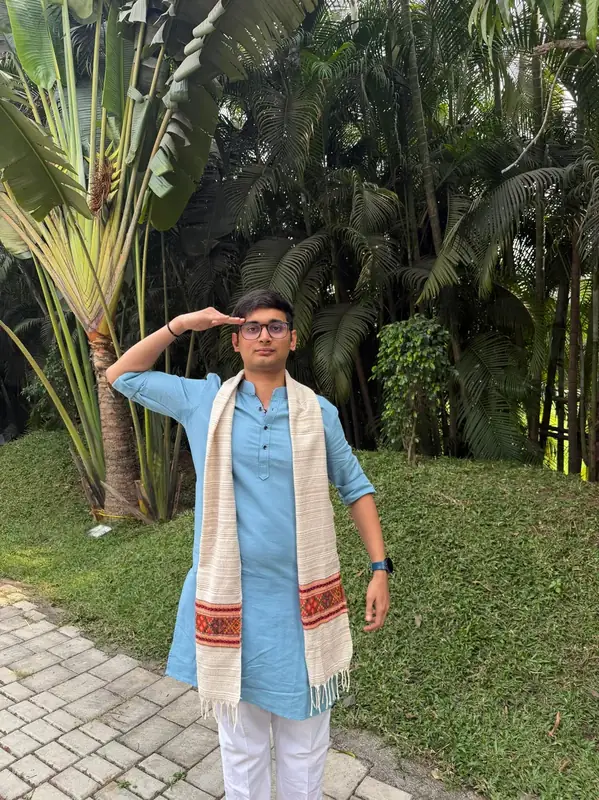 Darsh in a blue kurta saluting, surrounded by palm trees