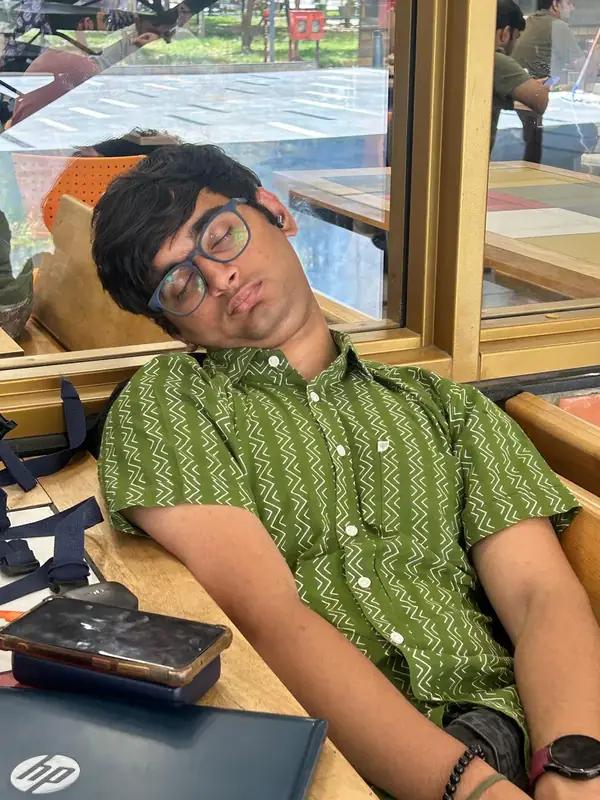 Darsh asleep on a chair at university, laptop open in front